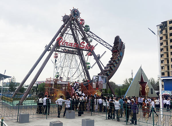 Fully installed pirate ship amusement ride in an outdoor amusement park with visitors lining up for the ride.