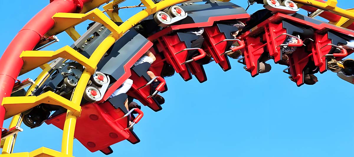 Gros plan sur des roues de montagnes russes qui s'agrippent à la piste par le haut, le bas et les côtés pour rester en sécurité sur la piste.
