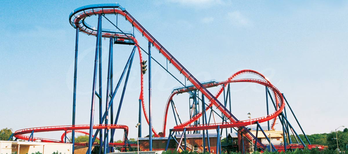 Grandes montagnes russes en acier lisse avec des rails rouges et des supports bleus sous un ciel clair.