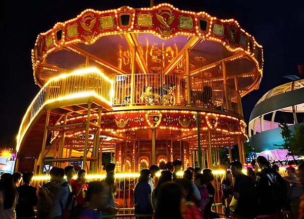 Two story double decker carousel glowing beautifully at night in Japan amusement park, popular family attraction with LED illumination and smooth rotation.