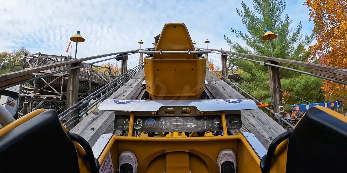 Onboard view from a wooden roller coaster train climbing the lift hill with classic track design