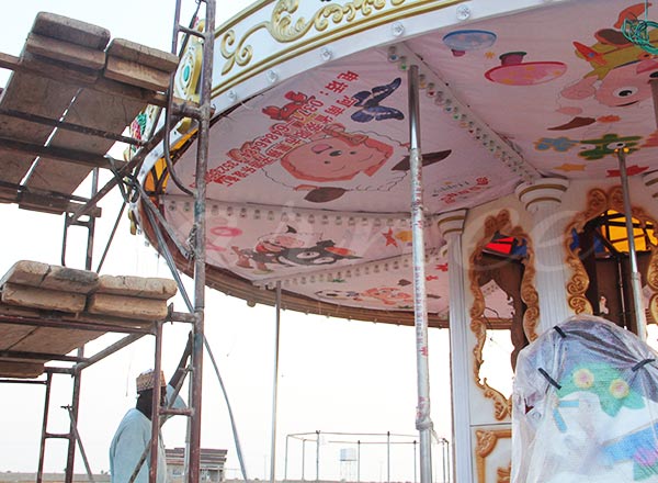 Carousel amusement ride roof and decorative panels being installed during assembly