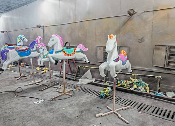 Proceso de pintura y acabado de los caballos del tiovivo del parque de atracciones durante la producción