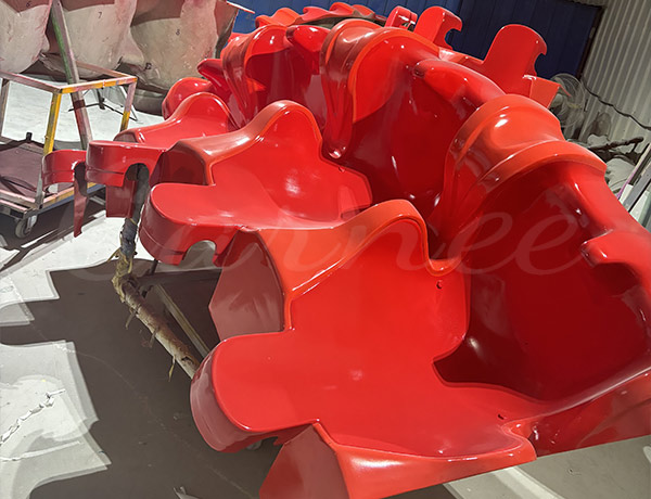 Asientos de pasajeros ergonómicos de fibra de vidrio roja para una atracción de torre de caída libre de feria, sometidos a la inspección final de calidad en la fábrica de Carnee Rides antes de ser montados en la estructura principal de la torre de caída libre.