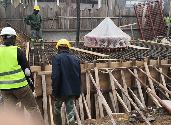 Trabajadores de la construcción alineando la brida de montaje central y los pernos de anclaje antes de verter el hormigón para una torre de caída.