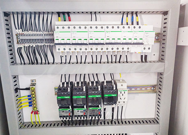 Primer plano de un armario de control eléctrico de una torre de descenso de calidad industrial, que utiliza componentes PLC auténticos de Schneider Electric y cableado de precisión para garantizar la seguridad absoluta de los sistemas de ascenso vertical y frenado magnético.