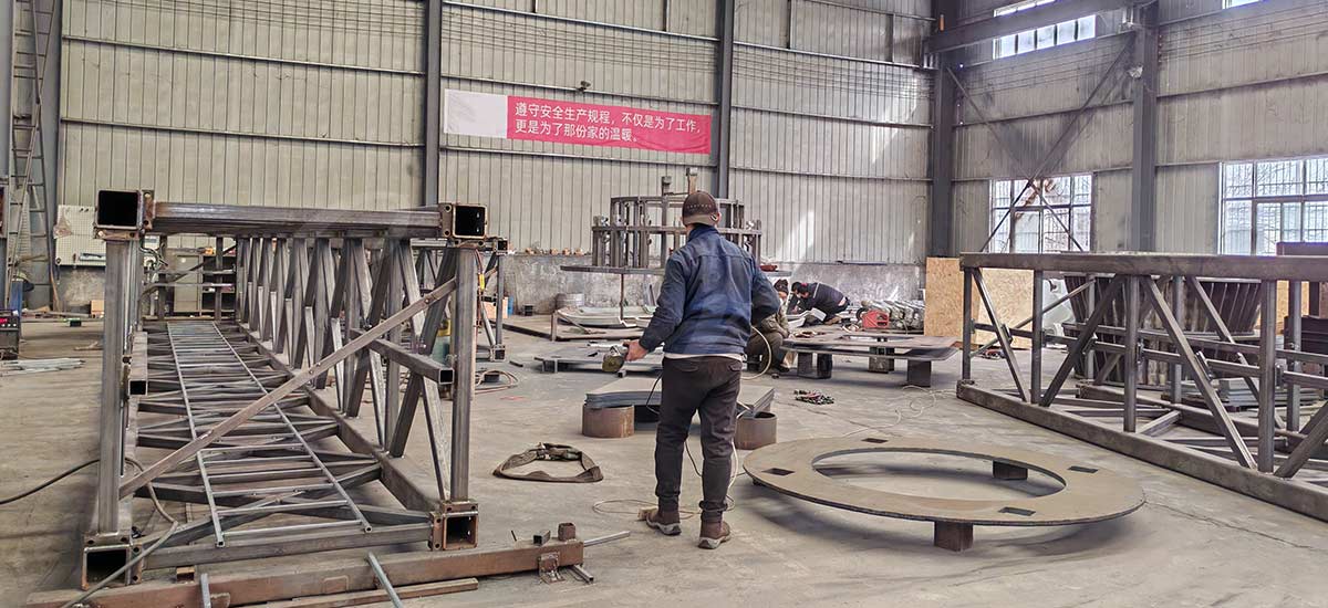Des soudeurs qualifiés fabriquent la structure du mât en acier au carbone à haute résistance pour une tour de chute commerciale dans l'usine de fabrication de Carnee Rides.