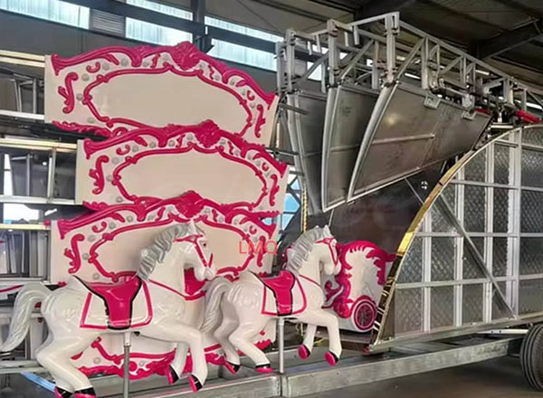 Частично сложенный переносной карусельный аттракцион на заводе, демонстрирующий сверхпрочные петли и стеклопластиковых лошадей на шасси прицепа.