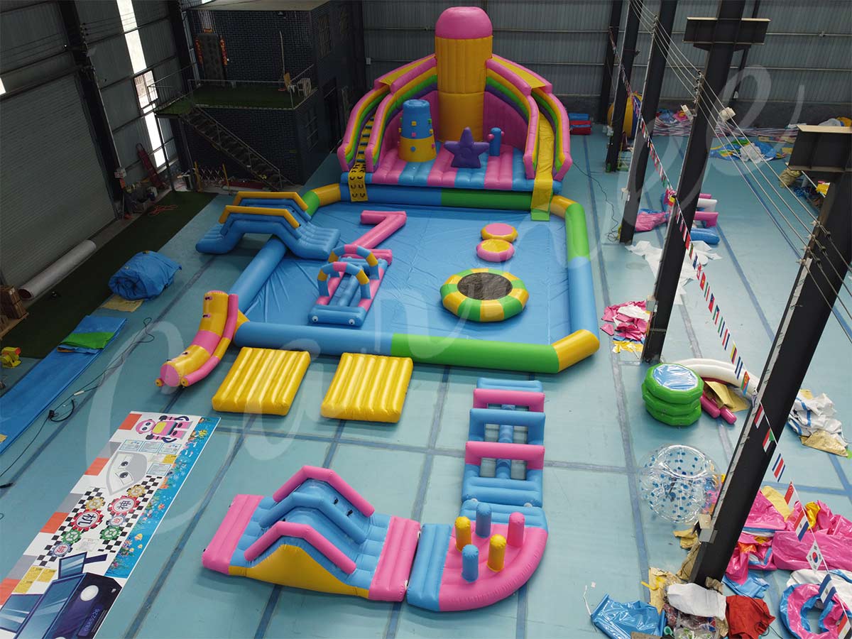 Instalación completa de parque acuático hinchable durante la prueba en fábrica, incluida torre de tobogán arco iris, piscina hinchable y elementos de juego de obstáculos acuáticos.