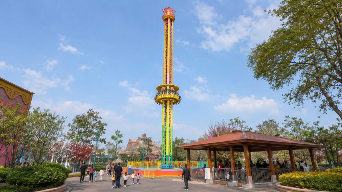 Manège de type « tour de chute » destiné à un parc d'attractions familial, comprenant une zone d'attente clôturée, une plate-forme d'embarquement, des allées pour les visiteurs et un aménagement extérieur du parc