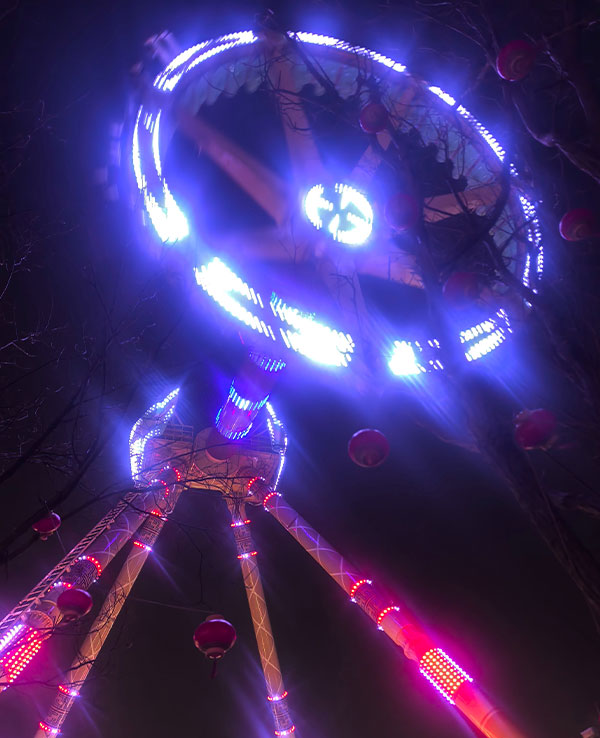 Funcionamiento nocturno de una atracción de emociones fuertes con péndulo de 360 grados, que cuenta con un sistema de iluminación LED programable y ofrece la sensación de ingravidez en la inversión total.